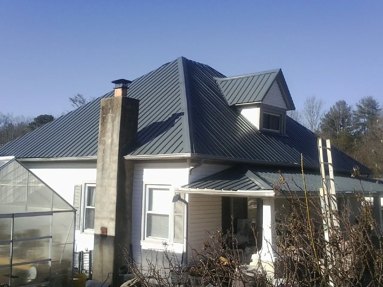 Dark blue standing seam metal roof on a white farmhouse with dormer — Slate & Tile Roof Repair by Roofing Brothers in Tamaqua