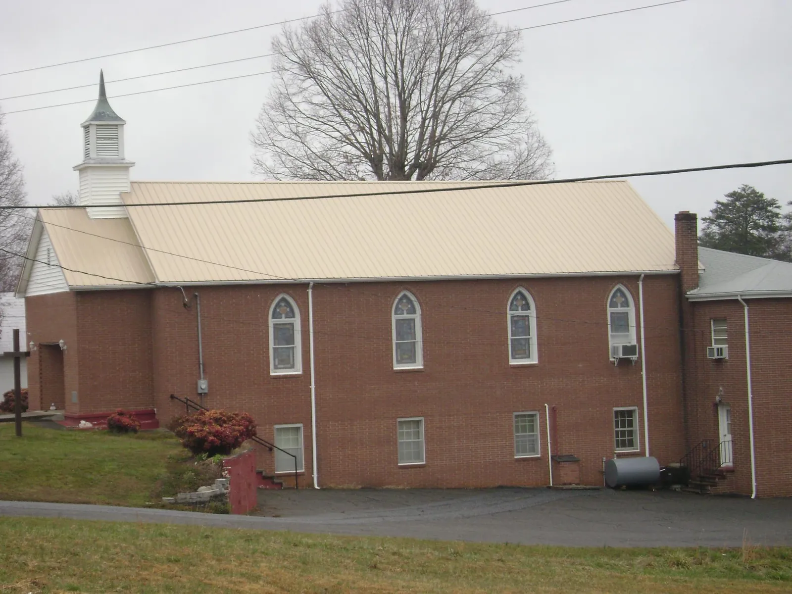 New tan metal roof on a brick church with a white steeple in Tamaqua