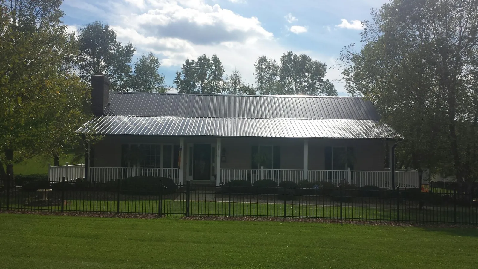 Gray metal roof on a brick ranch with a full width front porch — Gutter Guard Installation work by our crew in Tamaqua
