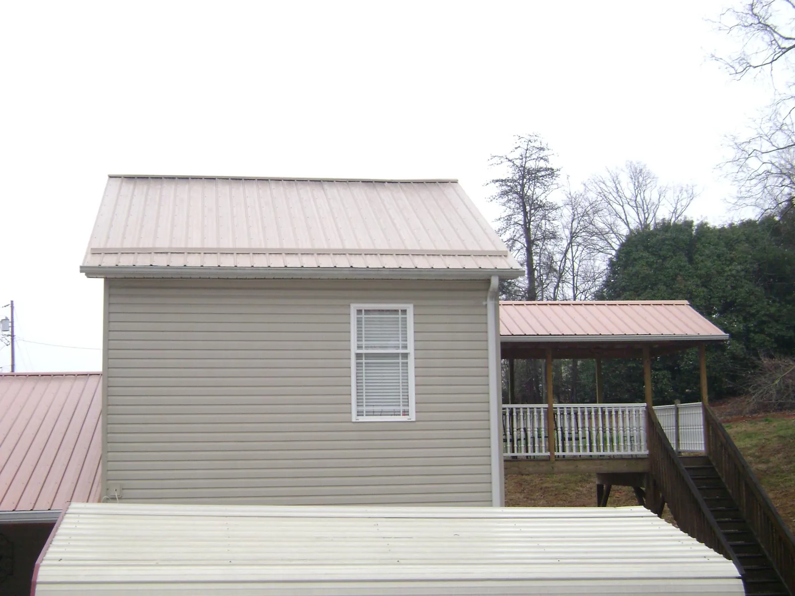 Tan metal roofs on a two story addition and attached porch, from a Roof Replacement job in Tamaqua