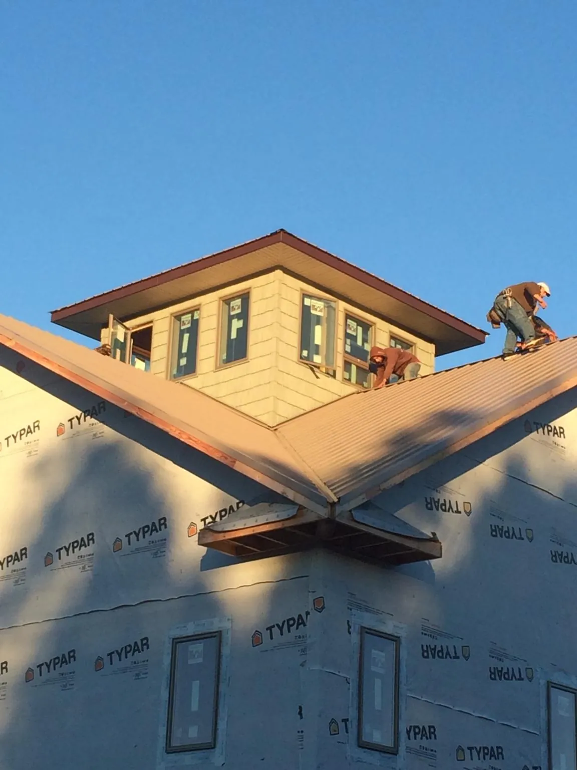 Roofers working around a rooftop cupola on a new metal roof at sunset — Roof Waterproofing in Tamaqua by Roofing Brothers